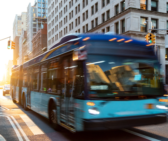 A New York City transit bus moving fast through the street